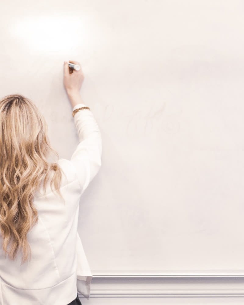 A woman writing on a whiteboard in an office