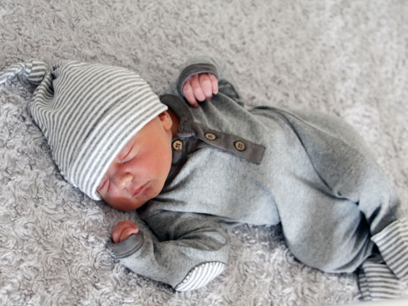 A newborn asleep in a striped hat