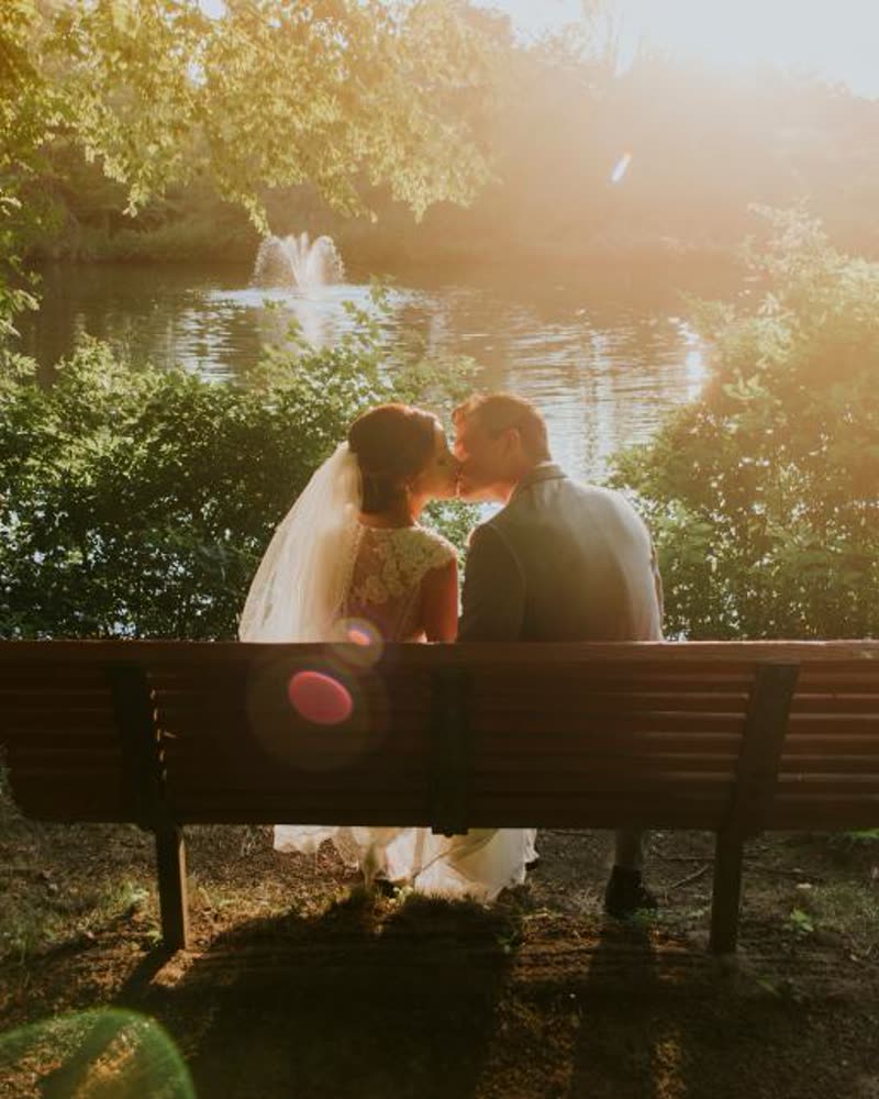 A couple sitting on a park bench at golden hour