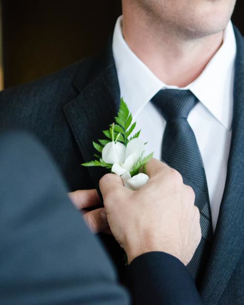 A boutonniere being pinned to a suit jacket